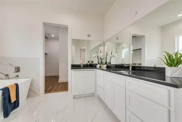 a bathroom with a tub a mirror and a shower