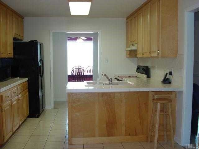 5845 Covered Bridge Road Clayton, NC 27527 - Photo 5 of 11 LOADS of cabinetry and COUNTERSPACE, CERAMIC TILE floors, TILE countertops and EAT-AT-BAR! OPEN to the BREAKFAST Room! Kitchen