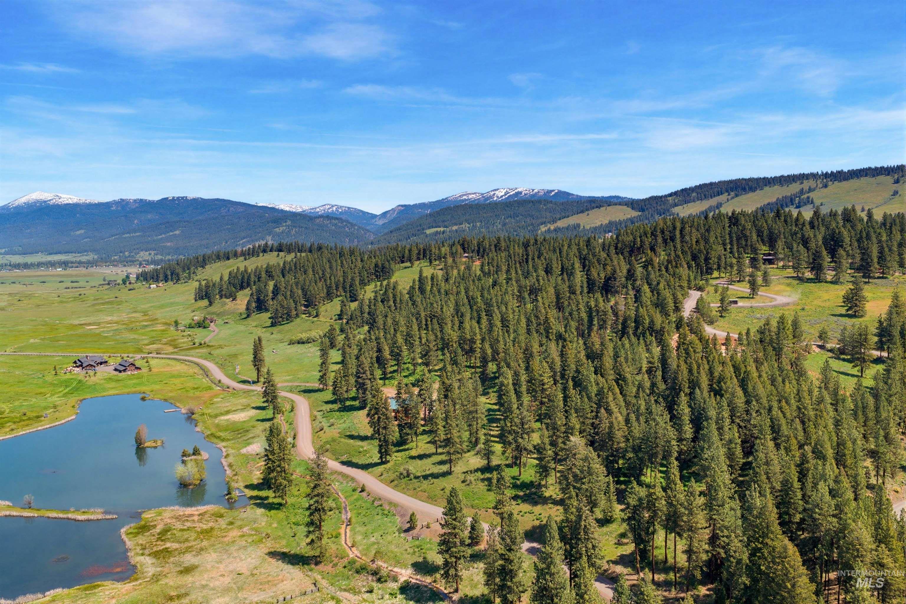 3322 Big Creek Road New Meadows, ID 83654 - Photo 6 of 50 Expansive landscape featuring a natural body of water, forested hillsides, a winding unpaved road, and distant snow-capped mountains