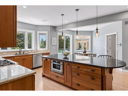 a kitchen with stainless steel appliances granite countertop a sink a stove and a wooden floors