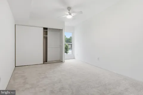 an empty room with a ceiling fan and a window
