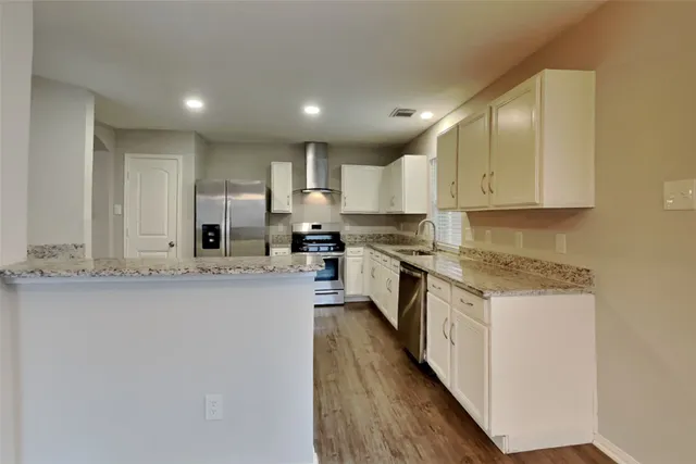 a kitchen with stainless steel appliances granite countertop a stove a sink and white cabinets