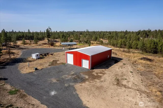 a view of a dry yard with a house and wooden fence