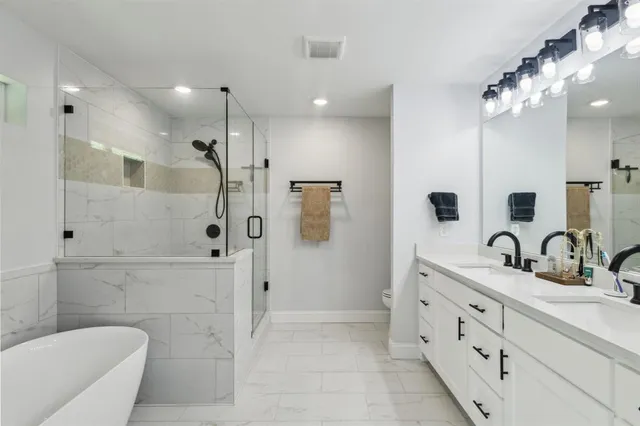 a bathroom with a double vanity sink a toilet a mirror and shower