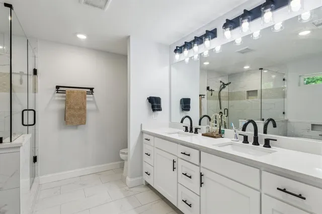 a bathroom with a double vanity sink mirror and shower
