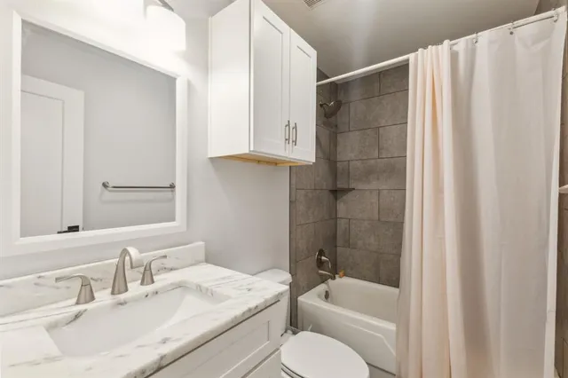 a bathroom with a granite countertop sink toilet and shower