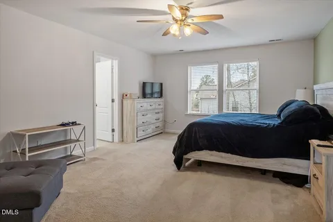 a bathroom with a toilet a sink a mirror and wooden floor