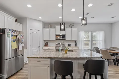 a kitchen with stainless steel appliances granite countertop a stove a sink dishwasher and microwave with wooden floor