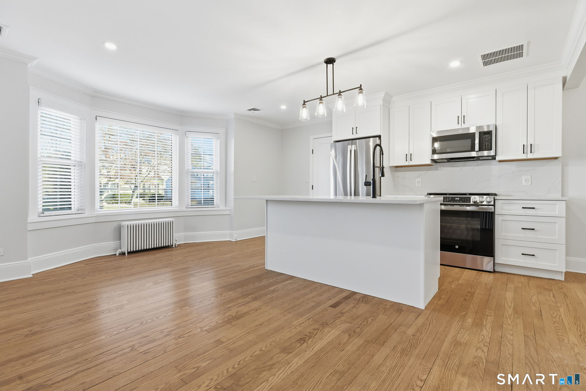 5 Bridge Street Norwalk, CT 06855 - Photo 3 of 11 a kitchen with stainless steel appliances kitchen island wooden floors and white cabinets