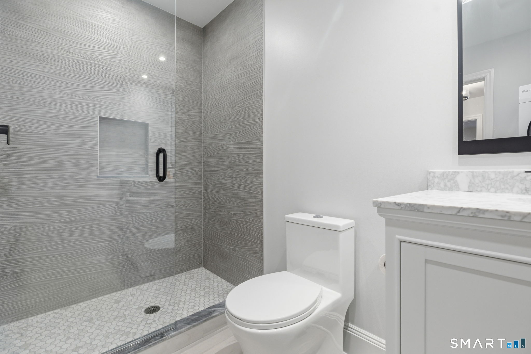 5 Bridge Street Norwalk, CT 06855 - Photo 8 of 11 a bathroom with a granite countertop toilet a sink a mirror and shower