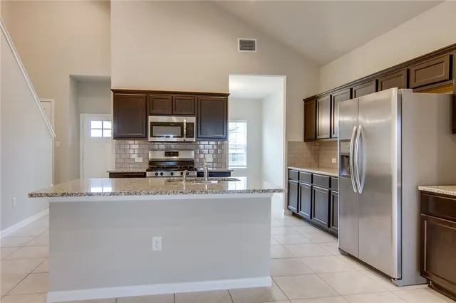 a kitchen with kitchen island a counter top space cabinets stainless steel appliances and a window