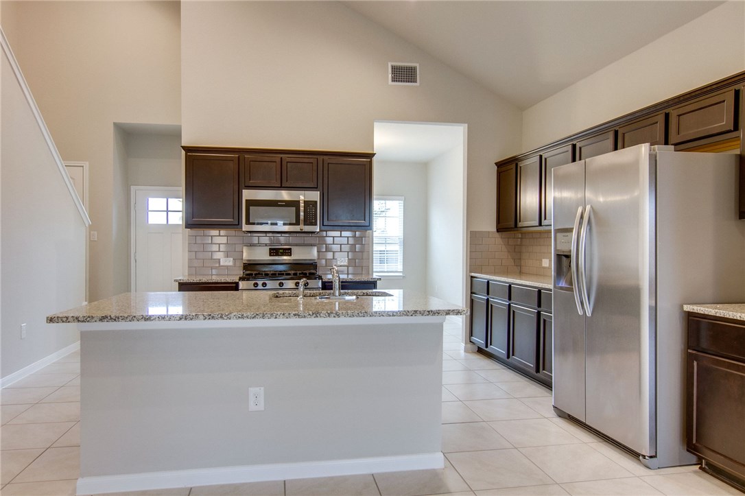 6916 Ranchito Drive Austin, TX 78744 - Photo 12 of 37 a kitchen with kitchen island a counter top space cabinets stainless steel appliances and a window