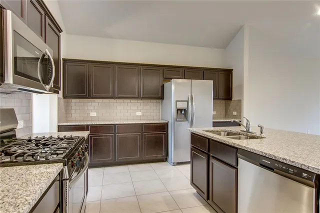 a kitchen with stainless steel appliances granite countertop a stove microwave and refrigerator