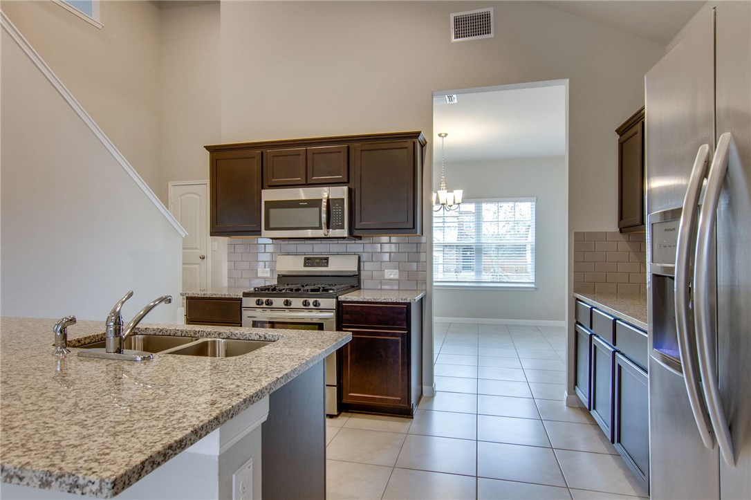6916 Ranchito Drive Austin, TX 78744 - Photo 15 of 37 a kitchen with stainless steel appliances granite countertop a sink stove and refrigerator