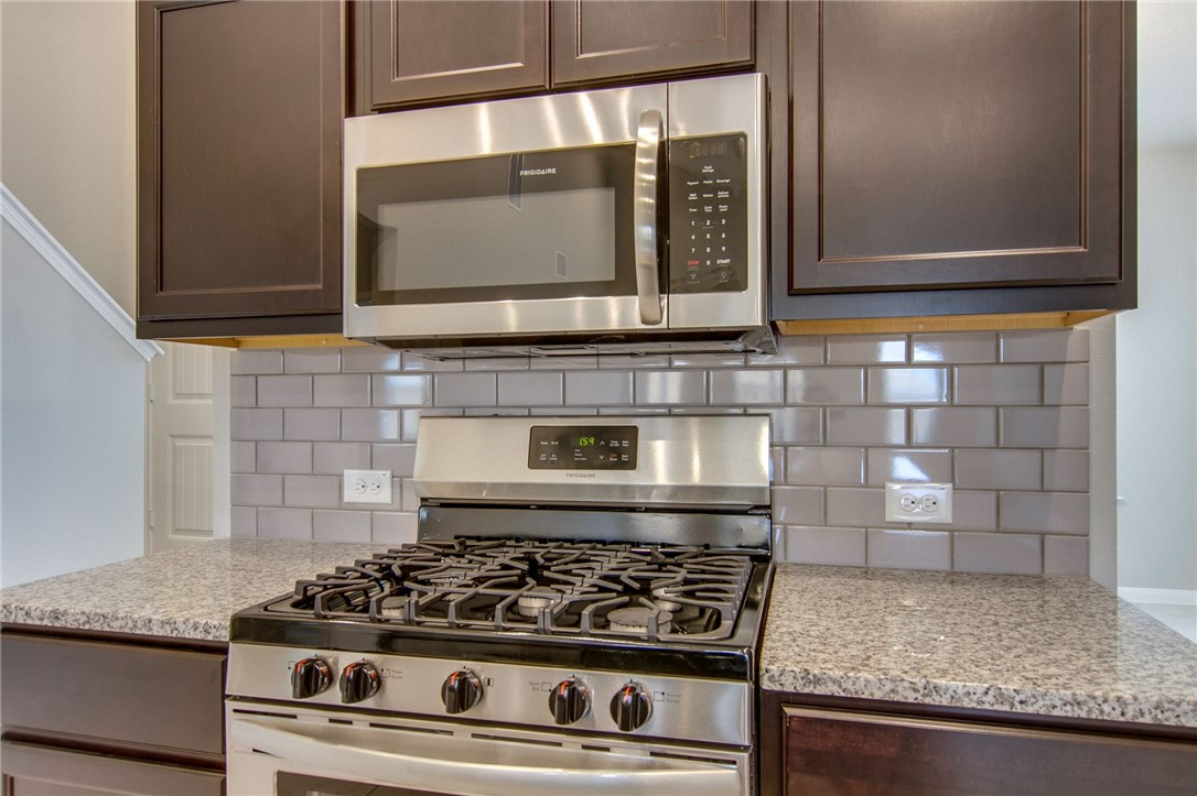 6916 Ranchito Drive Austin, TX 78744 - Photo 16 of 37 a kitchen with granite countertop a stove and a microwave