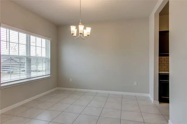 an empty room with chandelier fan and windows