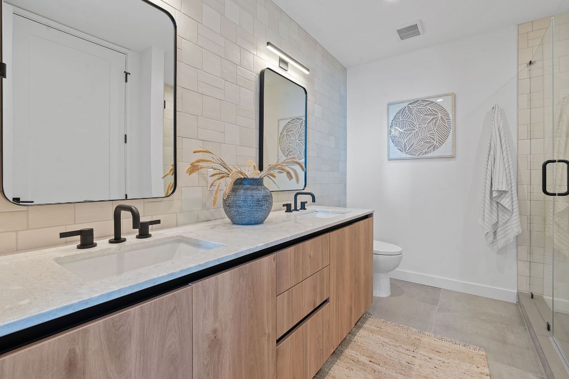 84 East Avenue, Unit 2410 Austin, TX 78701 - Photo 14 of 40 Representative of Property. Full bathroom featuring backsplash, double vanity, light tile patterned floors, and a stall shower