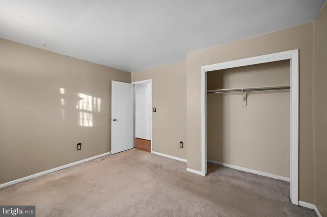 a view of an empty room with window and closet area