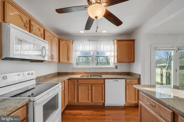 a kitchen with stainless steel appliances granite countertop a sink a stove cabinets and wooden floor