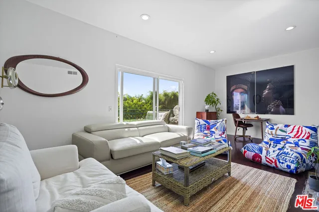 a living room with furniture two window and a flat screen tv