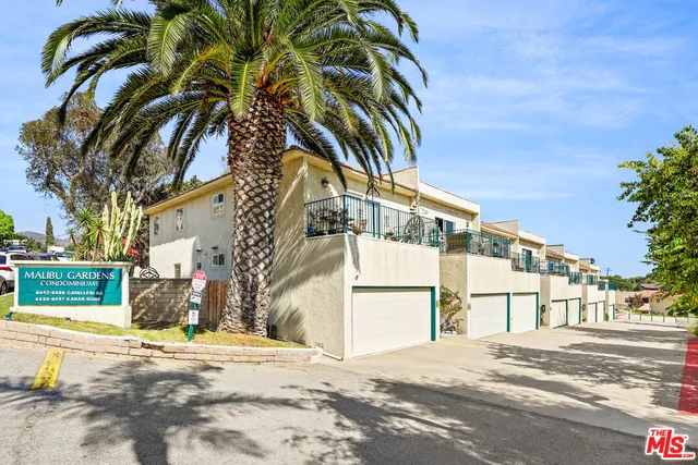 a view of a swimming pool with a lawn chairs under palm trees