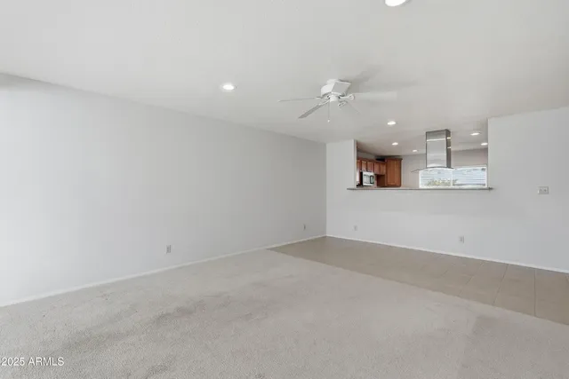 an empty room with a kitchen and a chandelier fan