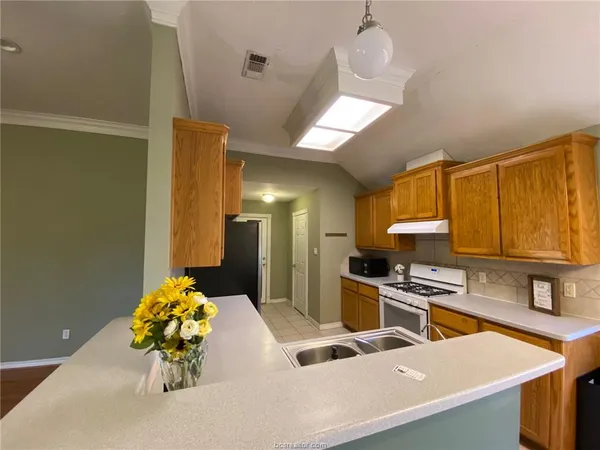 a kitchen with stainless steel appliances granite countertop a sink a stove and a wooden cabinets