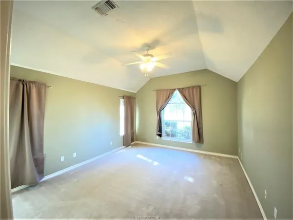 an empty room with a chandelier fan and windows