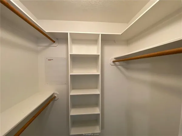 a view of walk in closet with empty racks