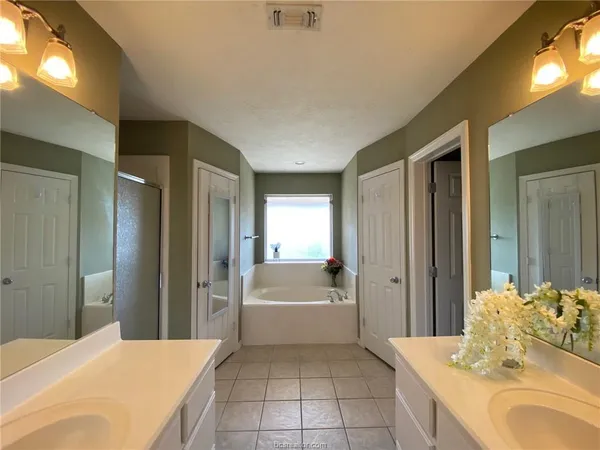 a en suite bathroom with a sink double vanity granite tub and shower