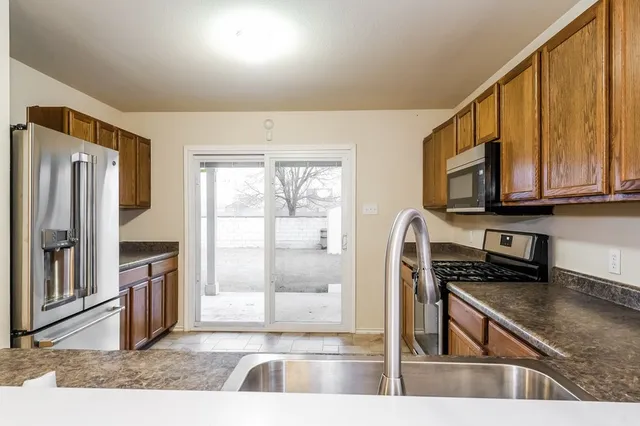 a view of a kitchen with stainless steel appliances granite countertop a refrigerator a stove top oven and a sink