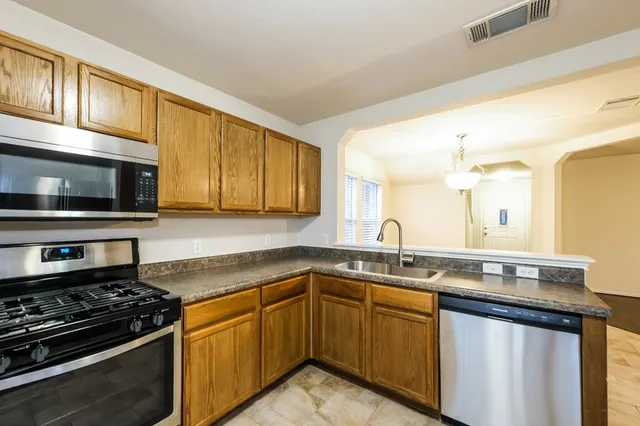 a kitchen with stainless steel appliances granite countertop a sink stove and microwave