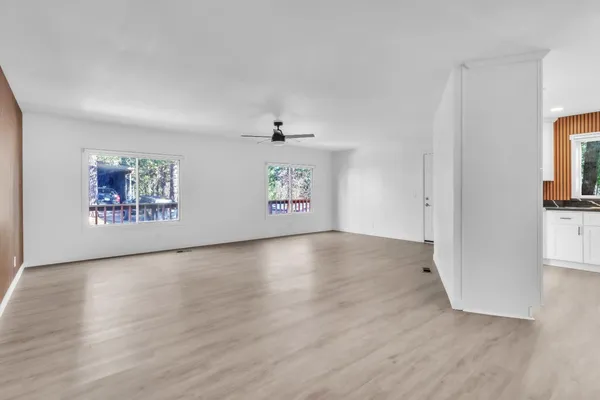 a view of an empty room with a window and wooden floor