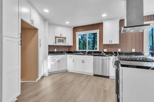 a kitchen with granite countertop white cabinets and white appliances