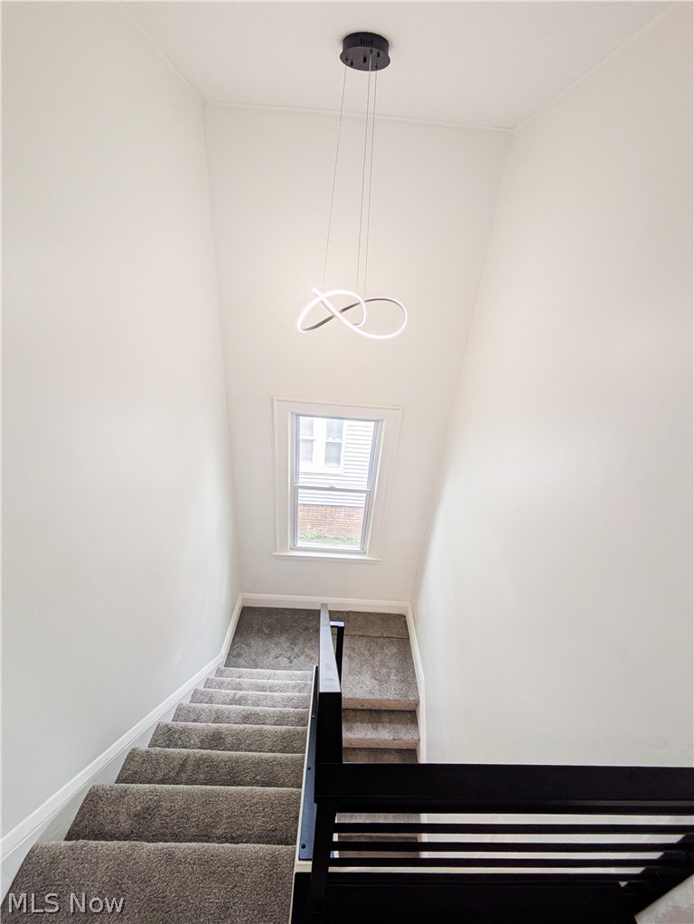 3554 Ludgate Road Shaker Heights, OH 44120 - Photo 25 of 50 Modern staircase with carpeted treads and black metal railing, illuminated by contemporary pendant lighting