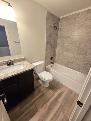 a bathroom with a granite countertop sink toilet a large mirror a bathtub and shower