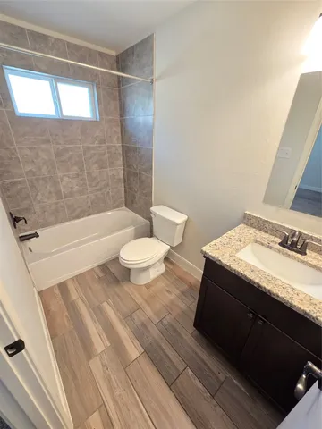 a bathroom with a granite countertop sink toilet a mirror and bathtub