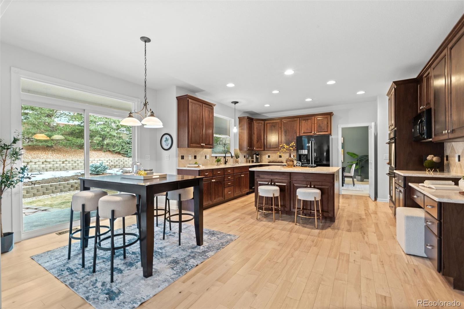 10683 Amesbury Way Highlands Ranch, CO 80126 - Photo 13 of 44 a kitchen with stainless steel appliances kitchen island granite countertop a table chairs and a view of living room