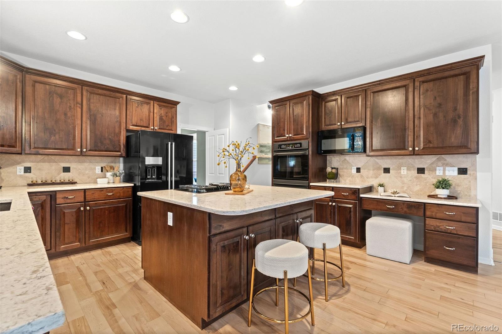 10683 Amesbury Way Highlands Ranch, CO 80126 - Photo 14 of 44 a kitchen with stainless steel appliances granite countertop a sink a stove a refrigerator cabinets and chairs