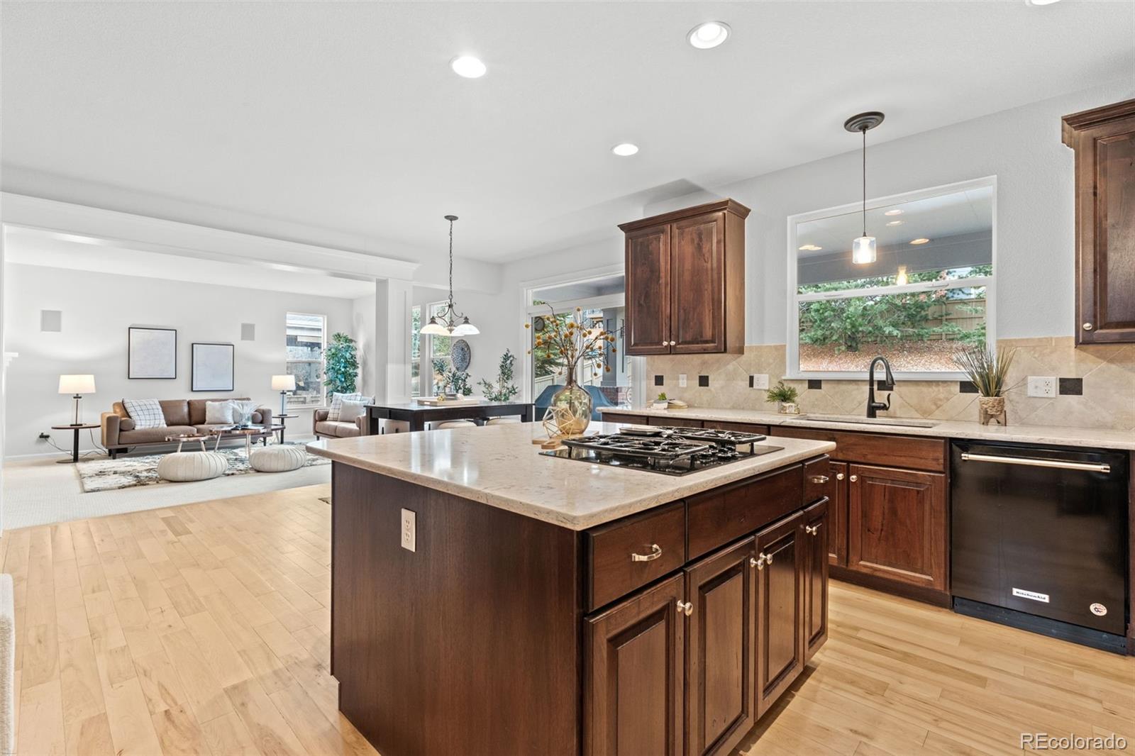 10683 Amesbury Way Highlands Ranch, CO 80126 - Photo 15 of 44 a kitchen with kitchen island granite countertop a sink stove and wooden cabinets