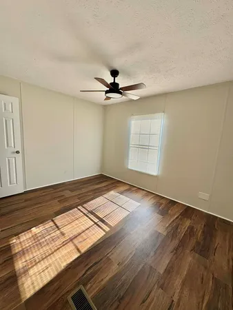 an empty room with wooden floor fan and windows