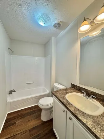 a bathroom with a granite countertop sink toilet and shower