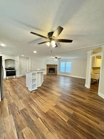 an empty room with wooden floor fireplace and windows