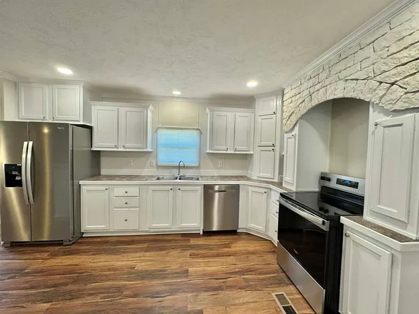 a kitchen with granite countertop a refrigerator stove and sink