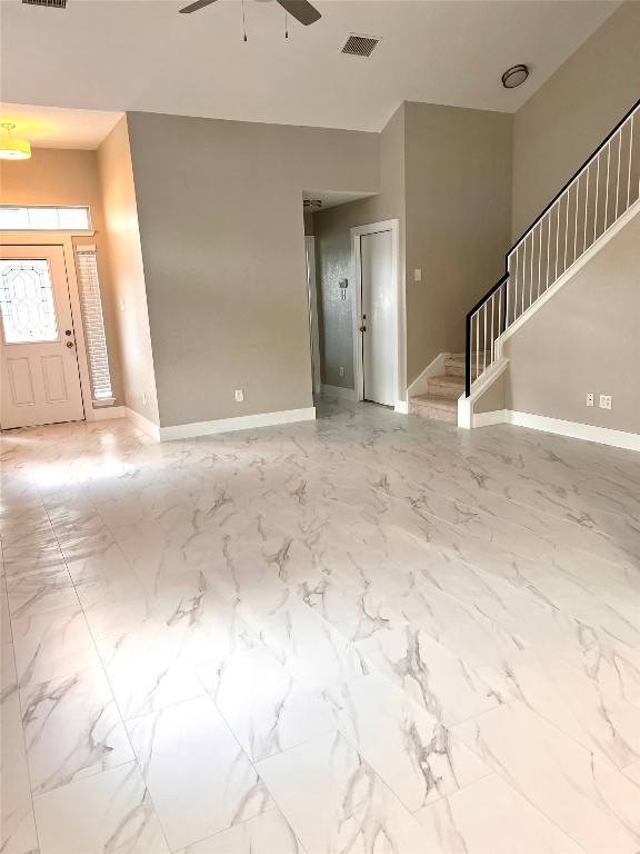 922 Gentry Drive Leander, TX 78641 - Photo 14 of 19 Unfurnished living room featuring stairs, a ceiling fan, and light marble finish floors