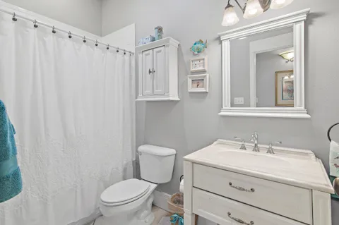 a bathroom with a sink a toilet a mirror a vanity and shower
