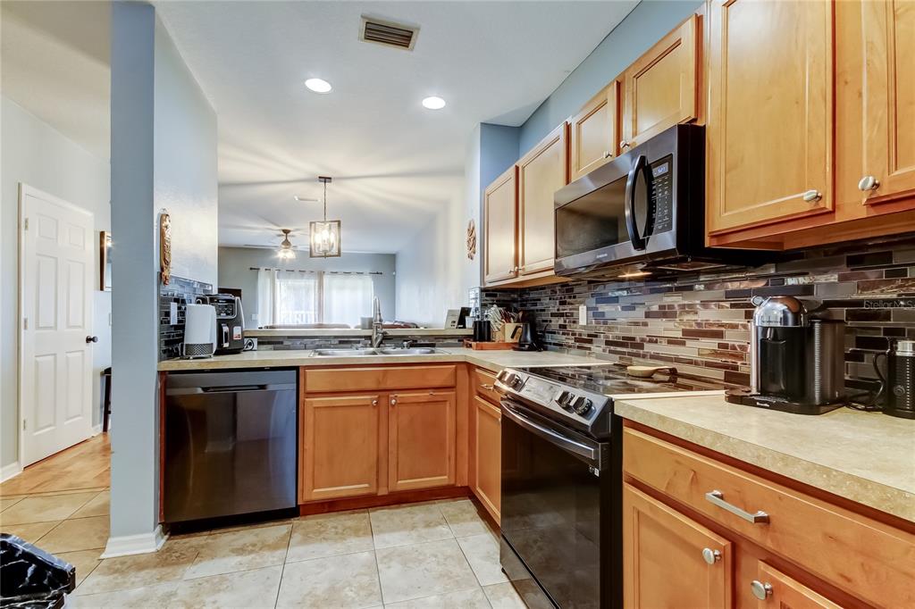 8504 Gablebend Way Tampa, FL 33647 - Photo 18 of 34 a kitchen with stainless steel appliances granite countertop a stove top oven a sink dishwasher and a microwave oven with large trees