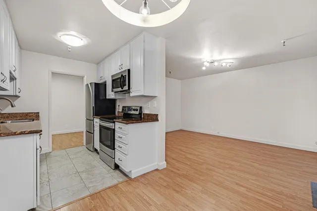 a kitchen with granite countertop a stove a sink and a refrigerator