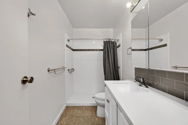 a bathroom with a sink a toilet and shower