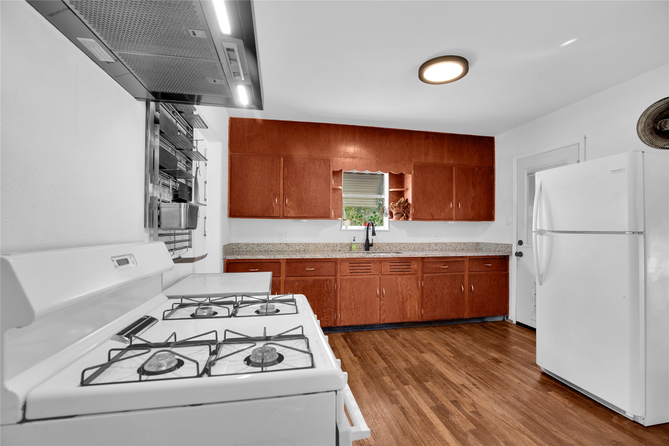 1607 East 4th Street Taylor, TX 76574 - Photo 8 of 32 Kitchen featuring white appliances, range hood, wood finish cabinetry, dark wood-style flooring, and open shelves
